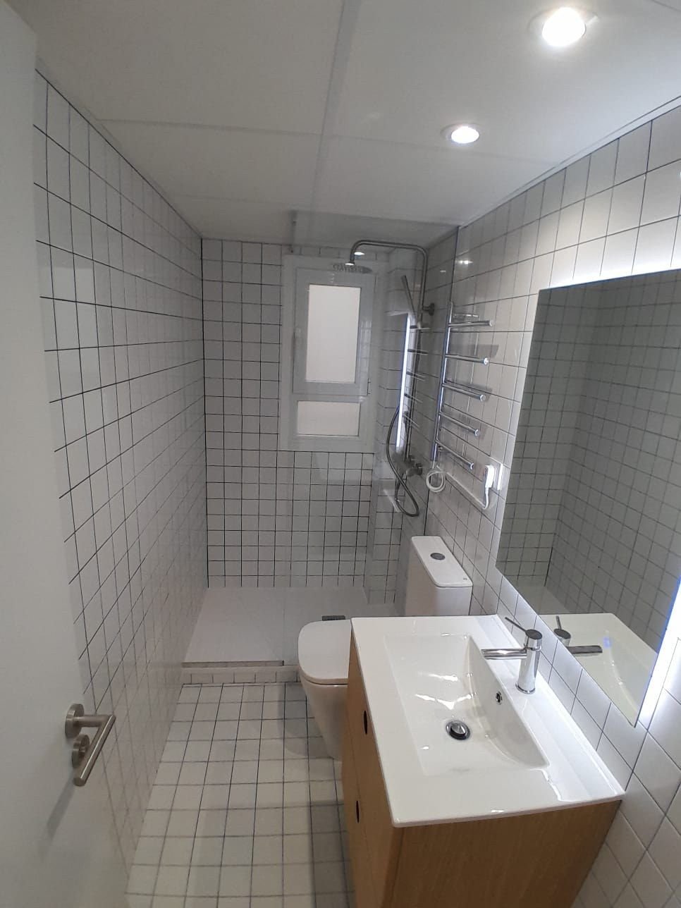 Baño de azulejo blanco con junta oscura