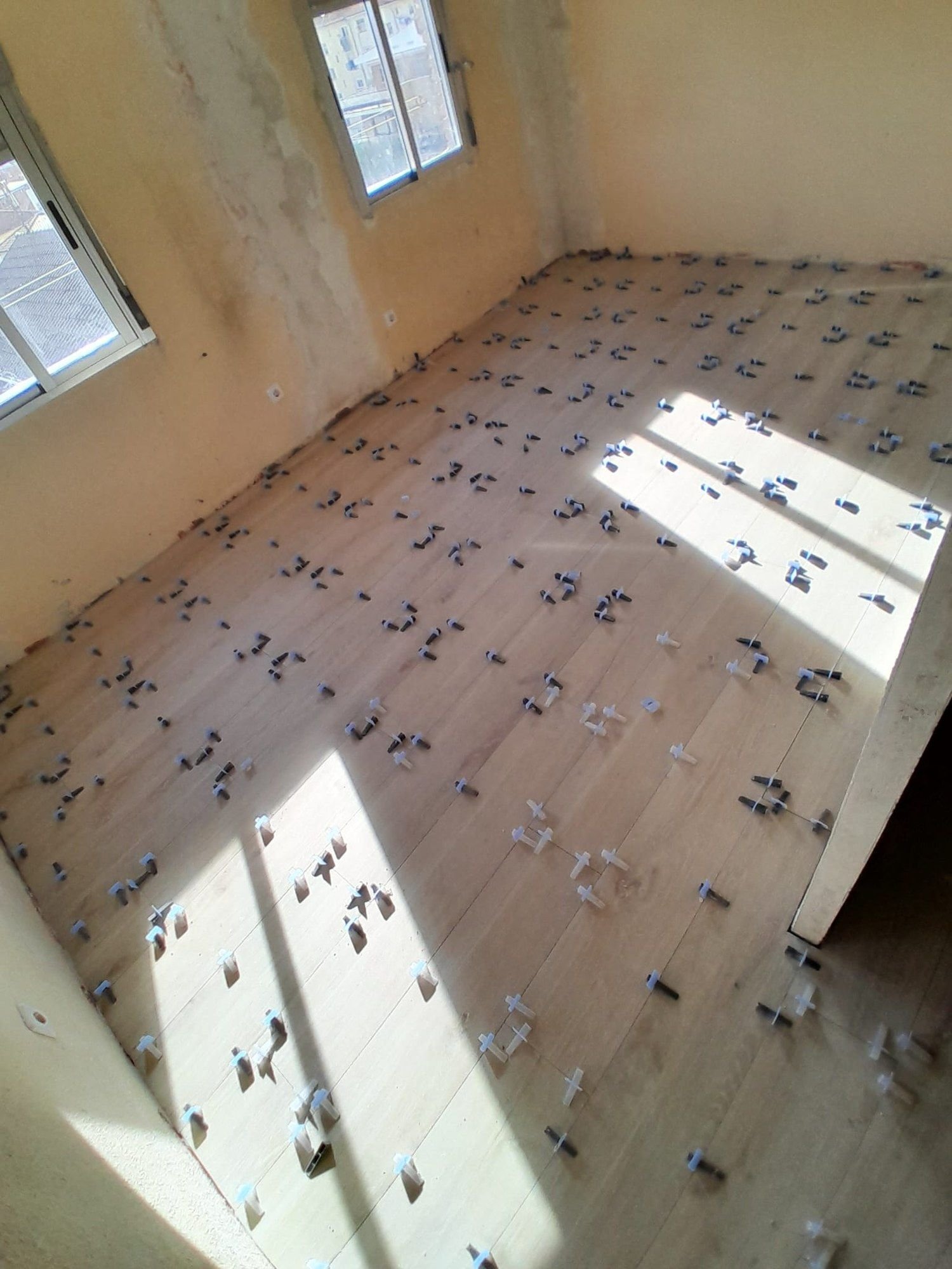 Solado de porcelánico imitación madera en colocación, con sol entrando por la ventana